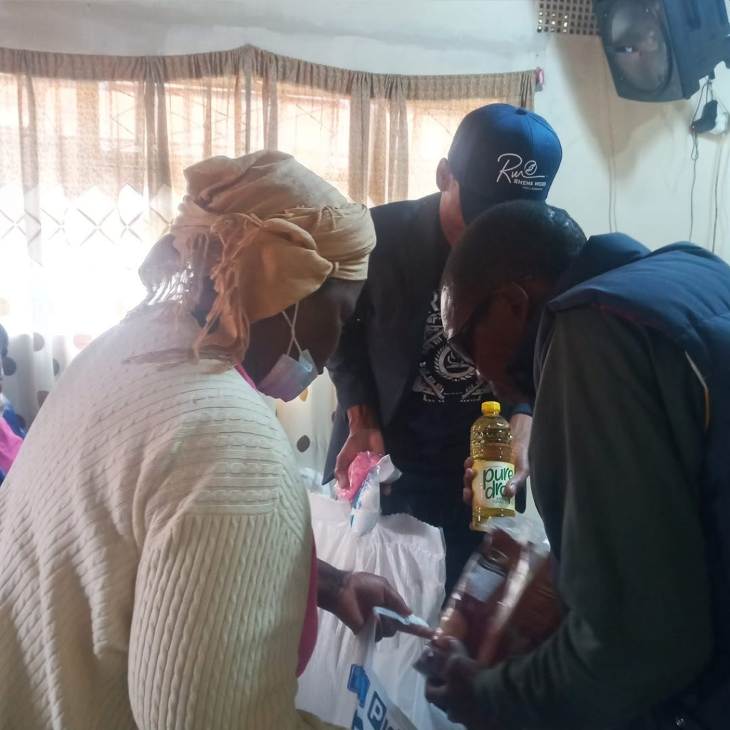 Apostle Keith handing food to lady in yellow shirt